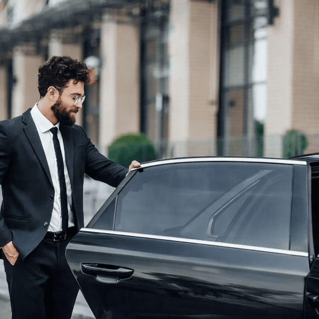Professional chauffeur opening car door